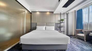 A modern hotel room with a large bed, a small seating area, and a view of the outdoors.