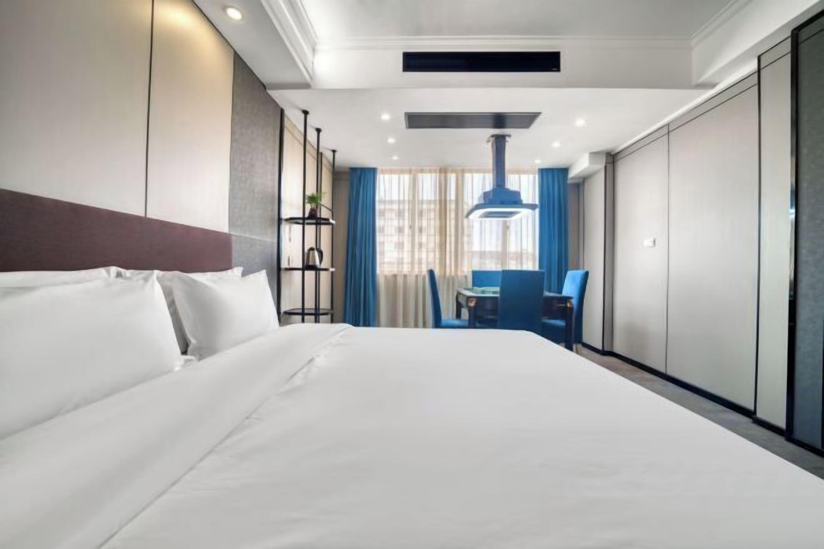 Ein Hotelzimmer mit einem großen Bett, einem Schreibtisch mit Stuhl und einem Fenster mit Vorhängen.