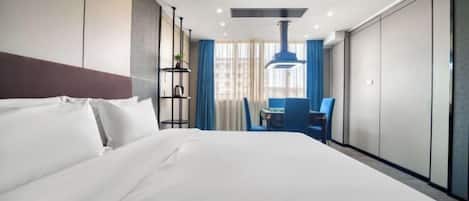 Habitación de hotel con una cama grande, un escritorio con silla y una ventana con cortinas.