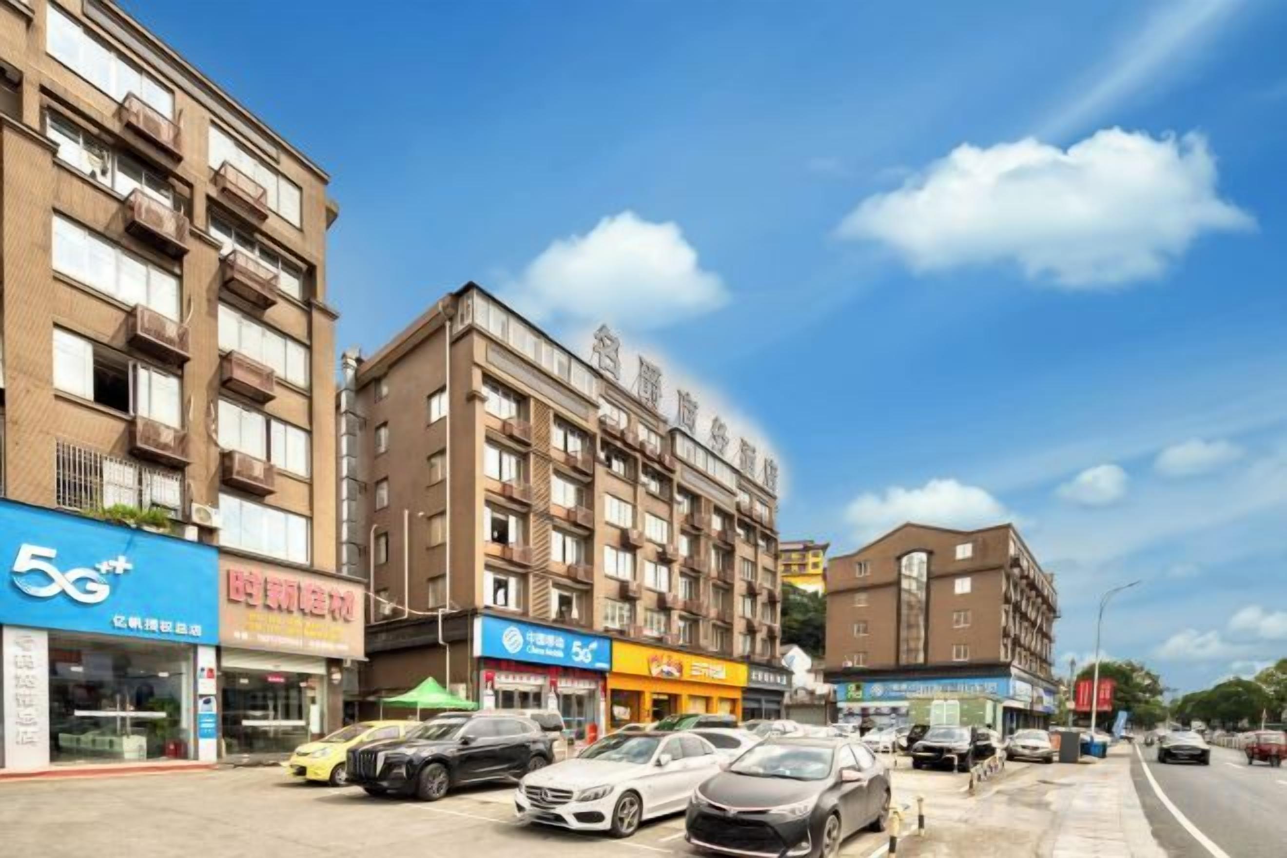 A multi-story building with commercial spaces on the ground floor, including a 5G+ sign, a restaurant, and a pharmacy.
