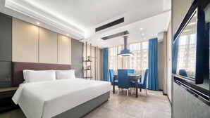 A modern hotel room with a large bed, a desk, and a dining area. - Mingjue Business Hotel (Wenling)