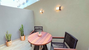 A small patio with a round wooden table and two chairs, surrounded by potted plants. - Setai Yacht Garden - By Almare Flats (João Pessoa)