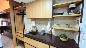 Una cocina compacta con armarios de madera, una encimera negra, una cafetera y una pequeña planta en maceta.