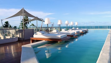 Uma área à beira da piscina com espreguiçadeiras e um toldo.