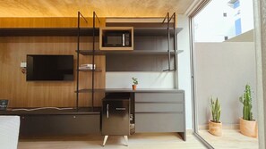 A compact kitchen with a microwave, a small refrigerator, and a TV mounted on the wall. - Setai Yacht Garden - By Almare Flats (João Pessoa)