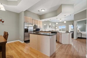 A spacious kitchen with wooden cabinets, stainless steel appliances, and pendant lighting.