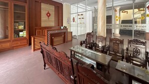 A traditional interior with wooden furniture, a glass display table, and a large column. - OYO 1246 Nha Khach Cuc Hau Can (Da Nang)