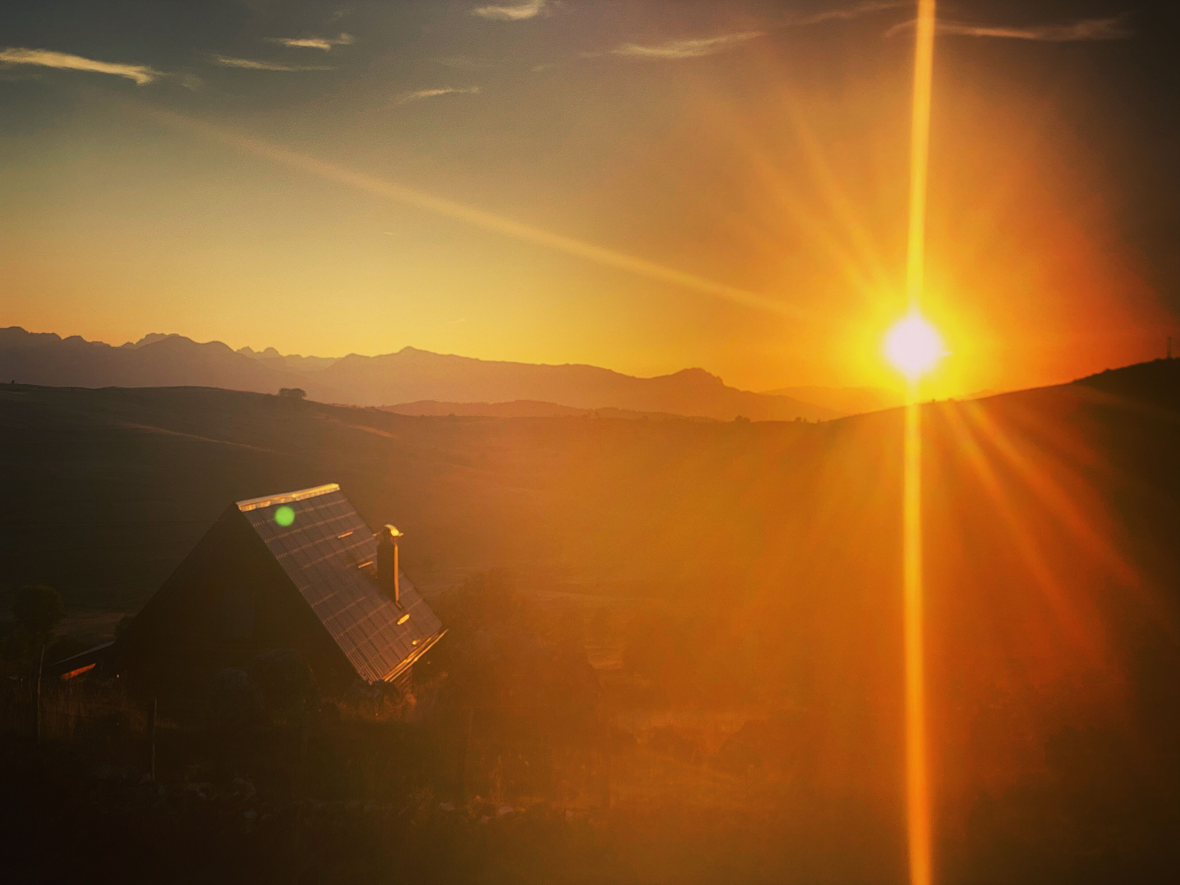 Un bâtiment équipé de panneaux solaires, offrant une vue sur des montagnes lointaines au coucher du soleil.