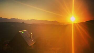 Un bâtiment équipé de panneaux solaires, offrant une vue sur des montagnes lointaines au coucher du soleil.