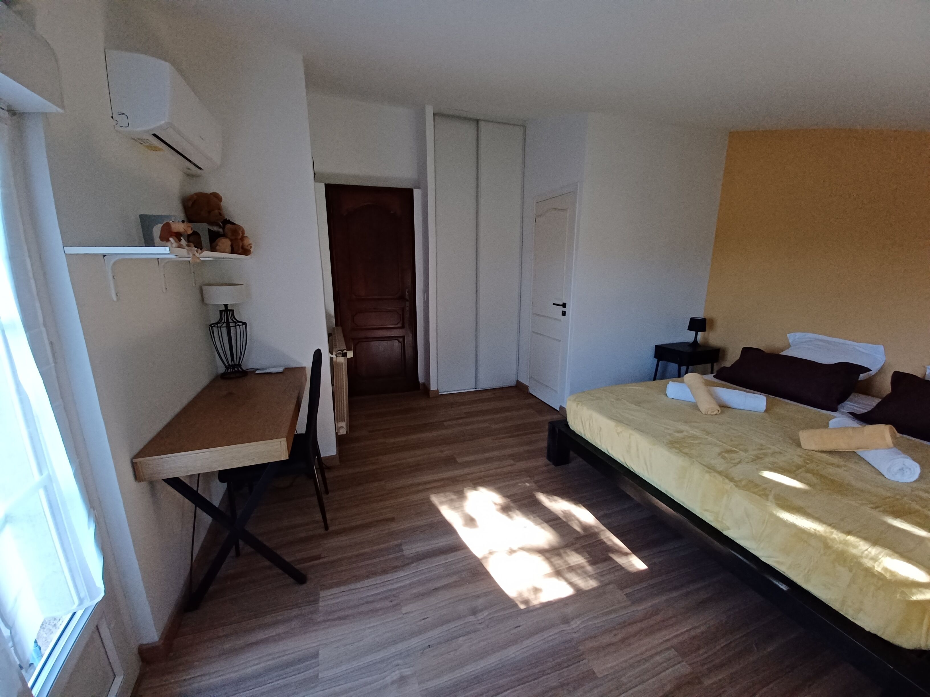 A bedroom with a bed, a desk, a chair, a lamp, and a radiator.