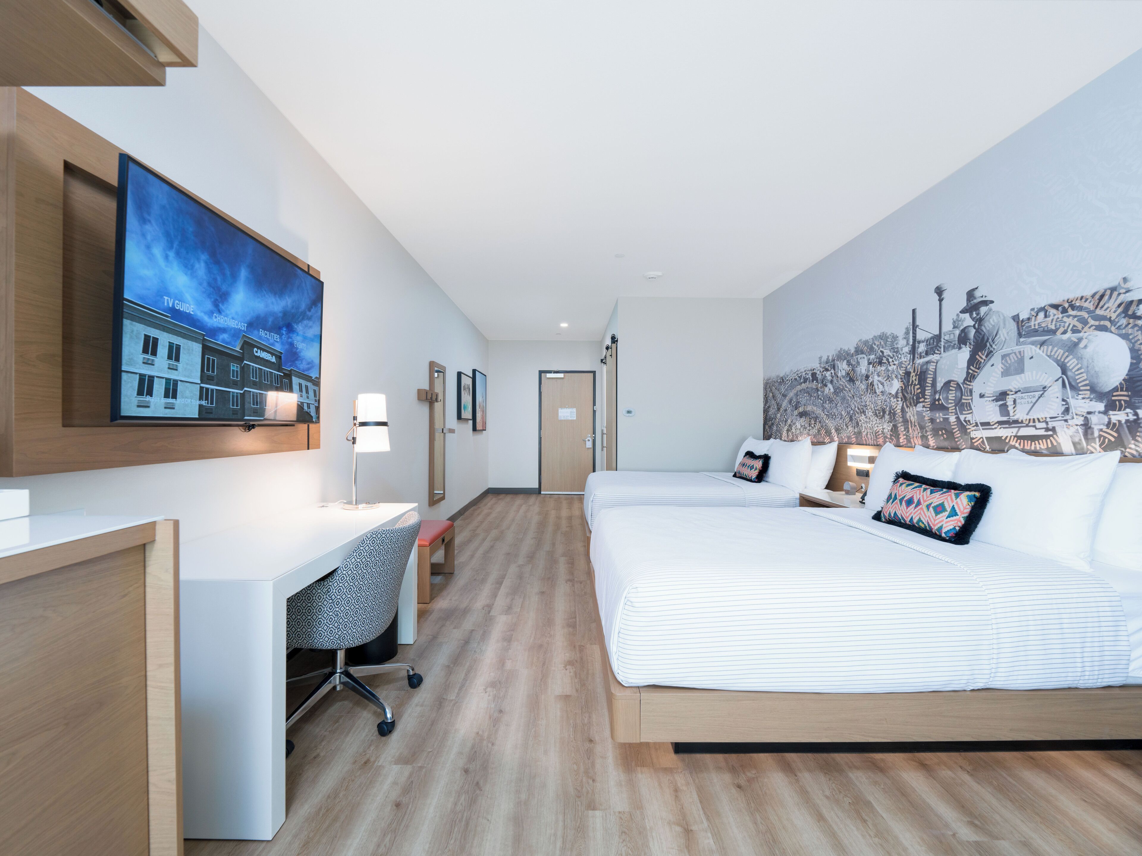 Et moderne hotelværelse med en stor seng, et skrivebord og et fjernsyn ophængt på væggen.