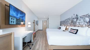 Et moderne hotelværelse med en stor seng, et skrivebord og et fjernsyn ophængt på væggen.