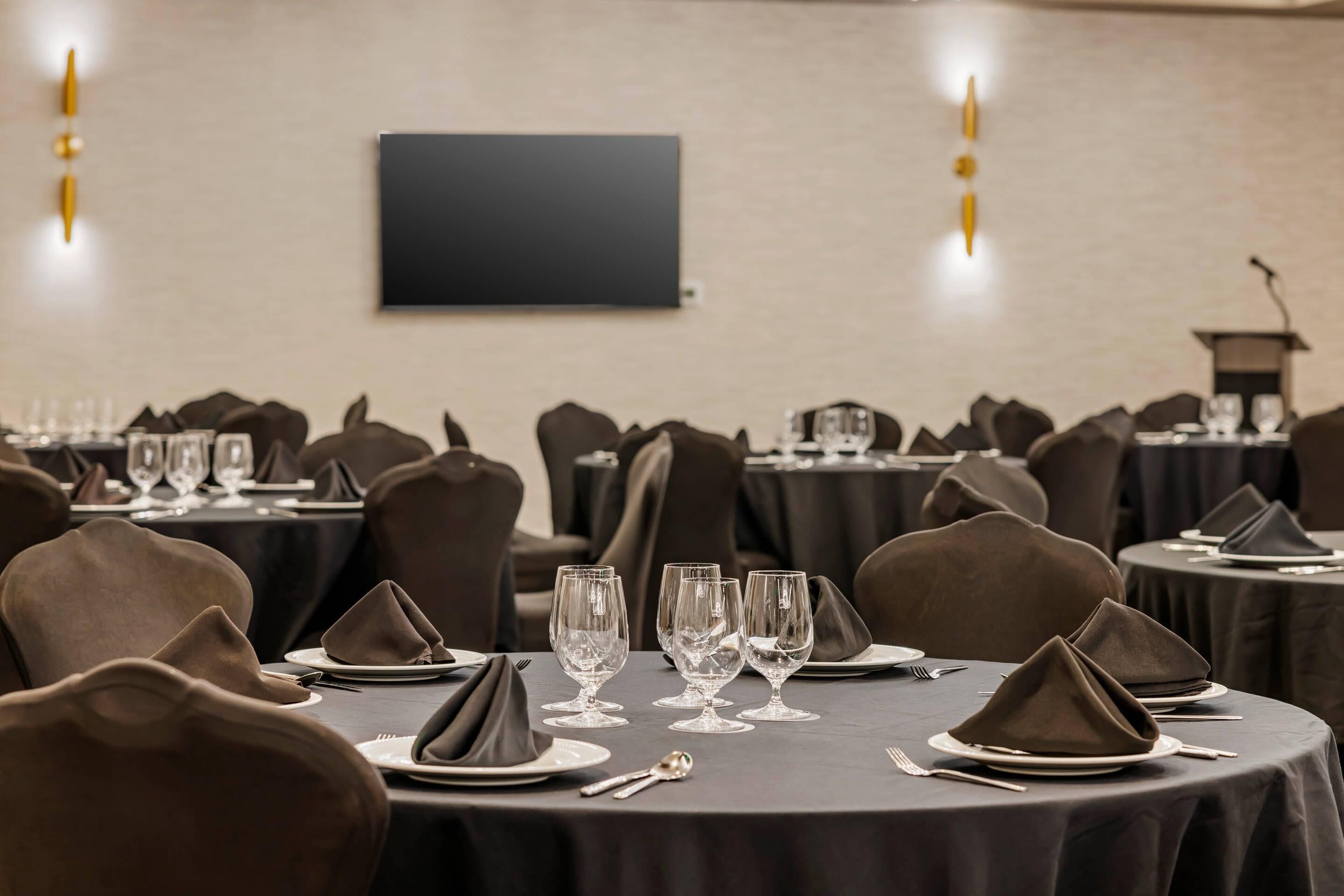 A conference room with round tables, each set with plates, glasses, and napkins.