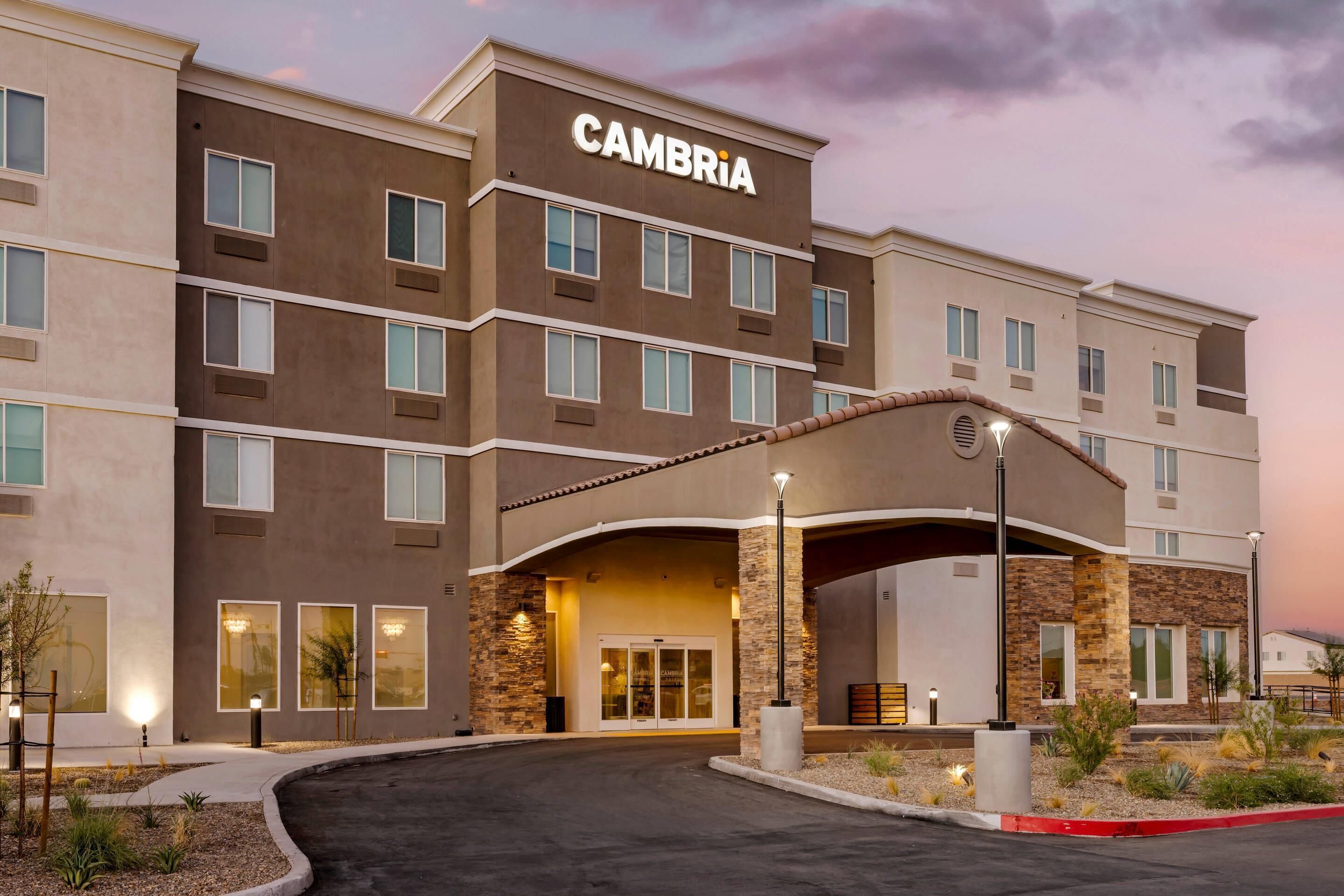 A multi-story hotel with a modern design, featuring a prominent entrance with a covered walkway and a sign that reads "CAMBRIA".