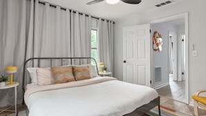 A bedroom with a bed, two bedside tables with lamps, a door, and a colorful striped rug. - Modern Cottage in Columbus (Columbus)