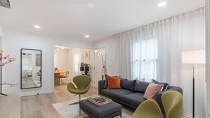 A modern living room with a grey sofa, green armchairs, and a dining area in the background. - Modern Cottage in Columbus (Columbus)