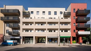 A multi-story building with balconies, a blue van parked in front, and a clear sky. - Łódź Wólczańska - Workspace & Balcony - by Rentujemy (Łódź)