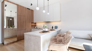 A modern kitchen with a central island, wooden cabinets, and pendant lighting. - Łódź Wólczańska - Workspace & Balcony - by Rentujemy (Łódź)