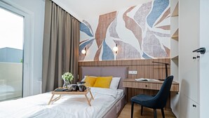 A modern hotel room with a bed, a desk, and a chair. - Łódź Wólczańska - Workspace & Balcony - by Rentujemy (Łódź)