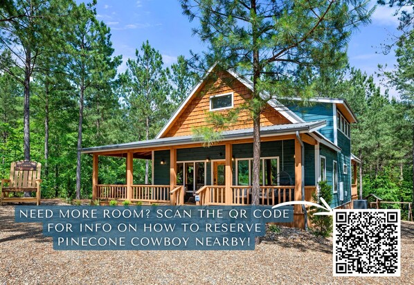 A lodge with a wooden exterior, a porch, and a sign indicating it is a Pinecone Cowboy property.