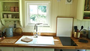 Een keuken met een raam, een spoelbak, een waterkoker en diverse keukengerei.