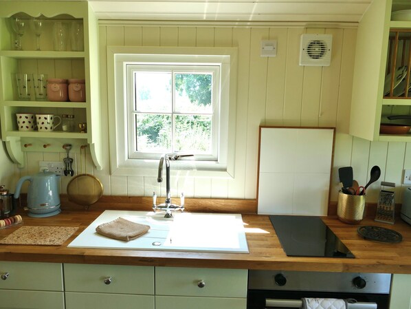 A kitchen with a window, a sink, a kettle, and various kitchen utensils. - Romantic Shepherd's Hut with hot tub. Ultimate Luxury experience. (Llandeilo)