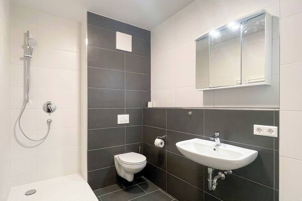 A modern bathroom with a shower, toilet, and sink.