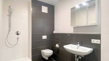 A modern bathroom with a shower, toilet, and sink.
