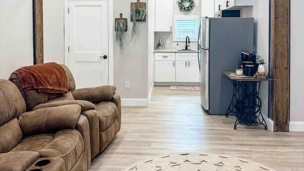 Un salon spacieux avec un canapé en cuir marron, un tapis décoratif et un ventilateur de plafond.