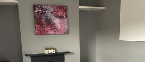 Une chambre à coucher avec un lit, une cheminée, une petite table et une étagère fixée au mur.