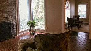 A living room with a fireplace, large windows, and a dining area. - 2-bedroom apartment in enchanting Fort Worth with AC (Fort Worth)