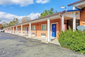 A row of motel rooms with individual doors and windows, a parking lot, and a clear sky. - Hotel O Relax Inn Lewisburg near I-64 (Lewisburg)