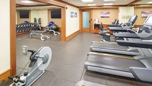 Une salle de sport équipée de tapis de course, de vélos elliptiques et de poids libres.