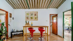 A dining area with a wooden table and two red bar stools, a framed picture on the wall, and a wooden floor. - Finca Umnisa  Choachi (Choachí)