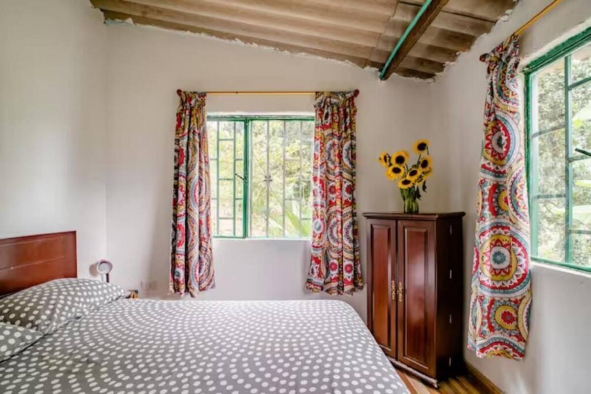 A bedroom with two beds, a wooden cabinet, and a window with patterned curtains.