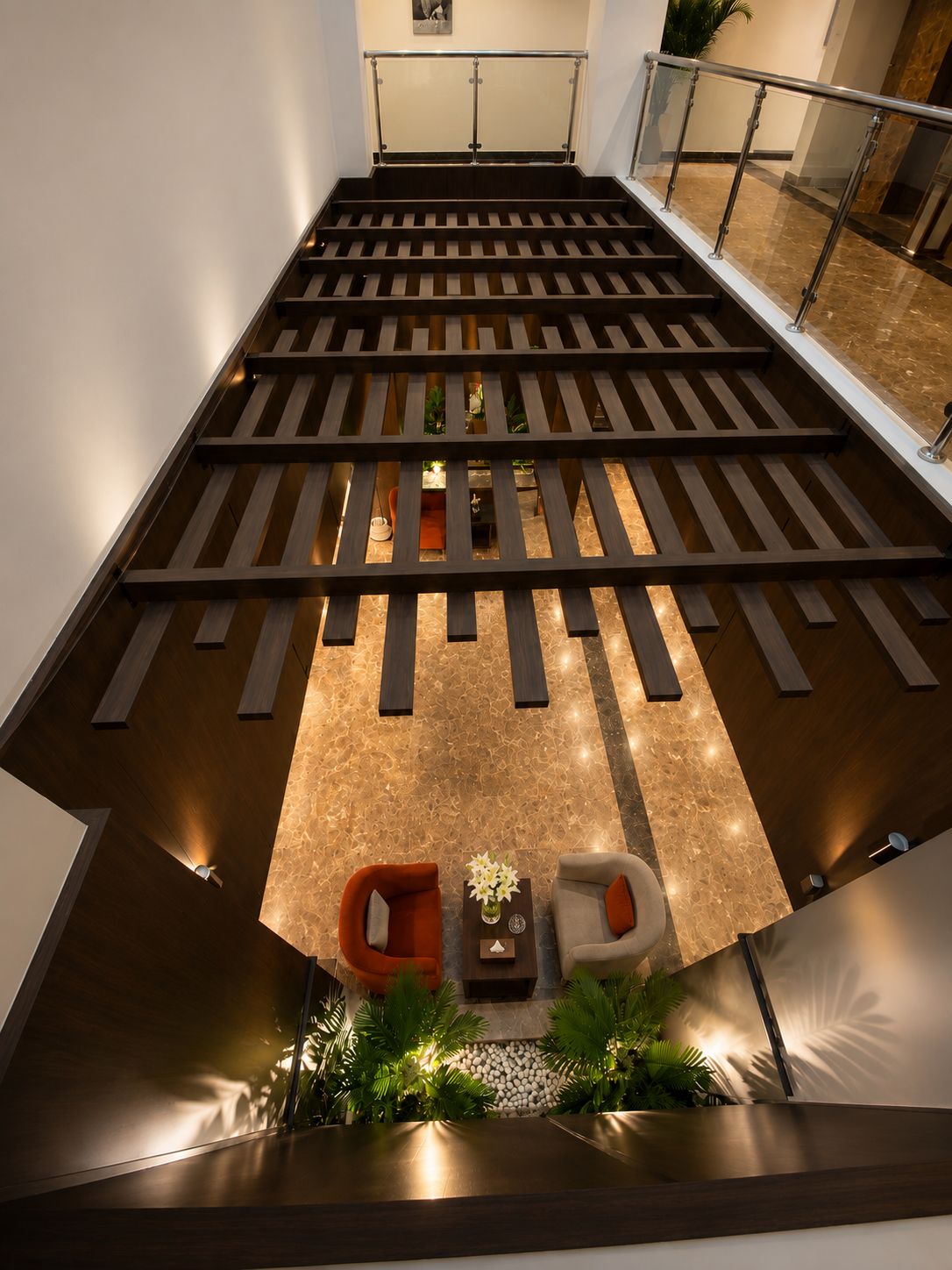 Un interior moderno con piso de listones de madera, una zona de estar con dos sillones y una mesita con un florero.