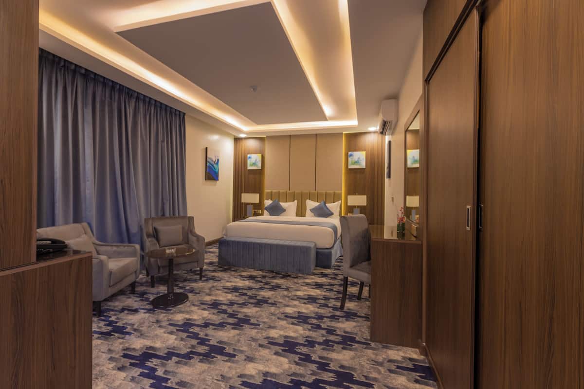 A hotel room with a bed, a sofa, a desk, and a wardrobe.