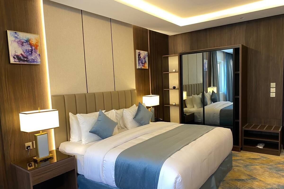 A hotel room with a large bed, bedside lamps, a wardrobe, and a mirror.