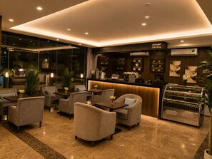 A modern interior with a bar area, seating, and a view through large windows. - Aman Hotel Almhalh (Abha)