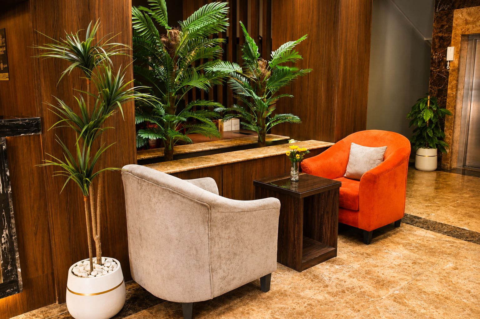 Un hall d’entrée avec un comptoir de réception, un espace détente comprenant un canapé et un fauteuil, ainsi que plusieurs plantes en pot.