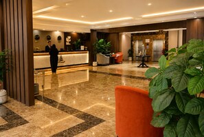 A hotel lobby with a reception desk, seating area, and a reception desk with a person standing. - Aman Hotel Almhalh (Abha)