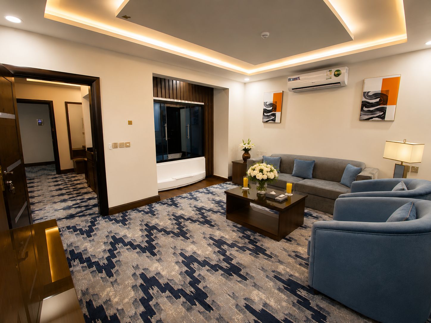 A modern living room with a sofa, armchairs, a coffee table, and a patterned carpet.