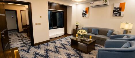 A modern living room with a sofa, armchairs, a coffee table, and a patterned carpet.