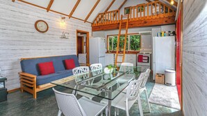 A compact living space with a loft bedroom, a dining area with a glass table, and a kitchenette.