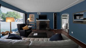 A living room with a fireplace, a sofa, a coffee table, and a television. - Comfortable home near river access trail (Redding)