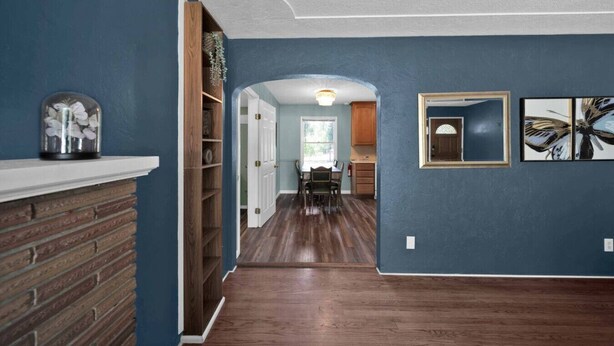 A hallway with a brick fireplace, wooden shelves, a dining area with a table and chairs, and a view into the kitchen. - Comfortable home near river access trail (Redding)