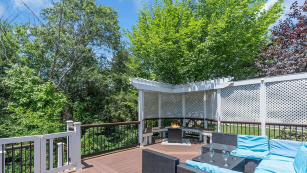 Une terrasse en bois avec des meubles d’extérieur, un foyer et une pergola.