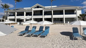 A beachfront hotel with multiple balconies, sun loungers, and umbrellas. - New! Just renovated coastal condo, Gated community, 10 min to beach by shuttle!  (Bonita Springs)