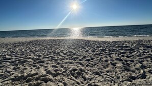 A beach with footprints leading to the water, a clear sky, and the sun shining. - New! Just renovated coastal condo, Gated community, 10 min to beach by shuttle!  (Bonita Springs)