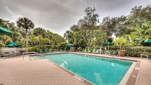 A rectangular pool with a 6 ft 2 in. depth, surrounded by a brick patio and green umbrellas. - New! Just renovated coastal condo, Gated community, 10 min to beach by shuttle!  (Bonita Springs)